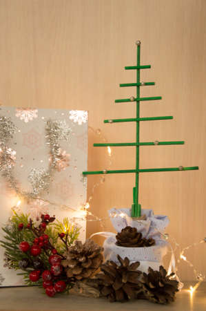 Christmas tree with garland lights and gift box on a wooden tableの写真素材