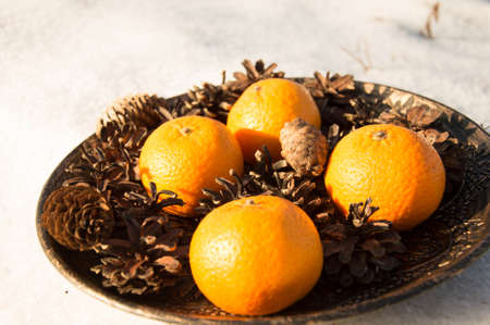Orange tangerines with cones in a bowl on a white backgroundの写真素材