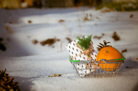 Shopping basket with tangerines and pine cones on the snowの写真素材