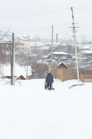 A woman with a child walks in the snow on a winter dayの写真素材