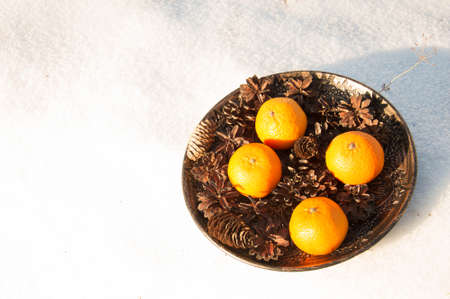 Tangerines in a metal plate on a white snow background.の写真素材