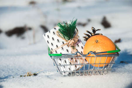Shopping basket with gifts and oranges on a snow backgroundの写真素材