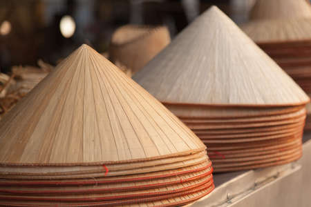 Traditional Vietnamese conical leaf hats for sale in market, warm coloursの写真素材