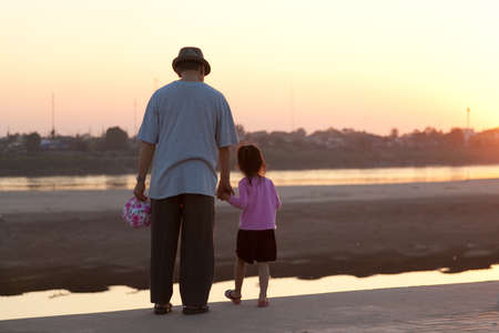 Mekong River, Vientiane, Laos at sunset, man and child looking towards Thailandのeditorial素材