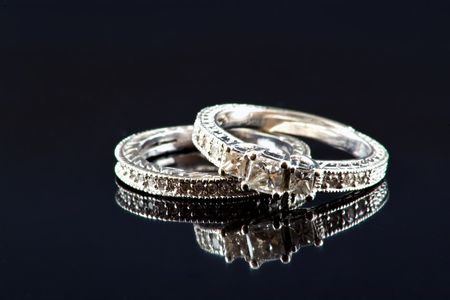 Diamond and white gold engagement ring and wedding band on a black reflective backgroundの写真素材