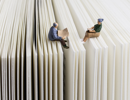 Miniature couple reading on a bookの写真素材