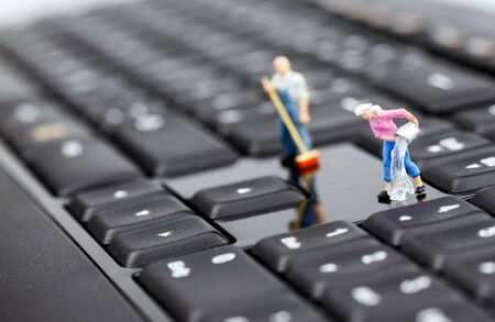 Miniature man and woman cleaning keyboardの写真素材