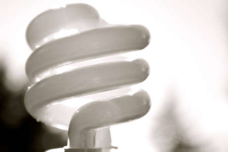 close-up of a compact fluorescent lightbulb on a blurry black and white background