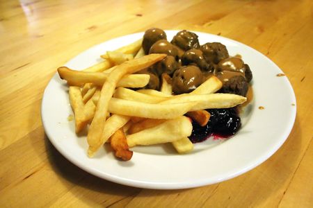 Swedish meatballs and french fries with gravy, on a wooden table