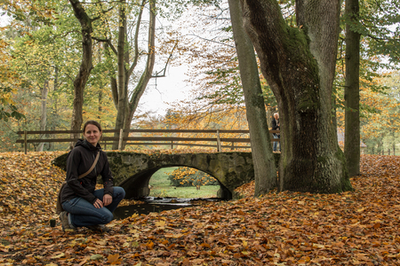 young girl is sitting next to the bridge over the riverの写真素材
