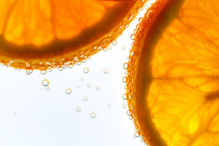 Fresh orange slice in water with bubbles on white background