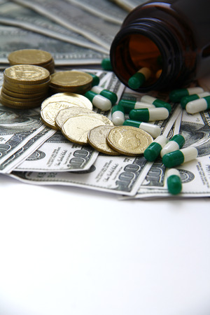 Expensive healthcare concept, Capsules and pills pouring from bottles, medicines on dollar on White Backgroundの写真素材