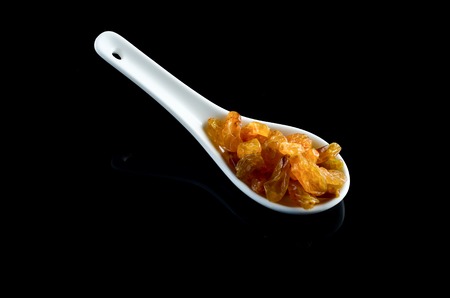Raisin in white spoon over black backgroundの写真素材
