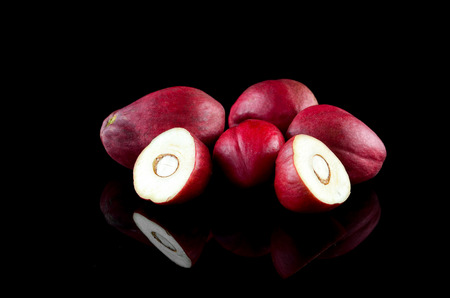 Fruit of Crown Of God, God's crown, Phaleria macrocarpa or Buah Mahkota Dewa inside the stone mortar on the top of the table with natural light.の写真素材