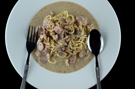 Delicious spaghetti carbonara with bacon and chicken ingredient sauce in white plate over black backgroundの写真素材