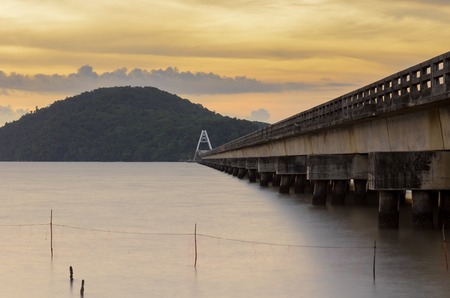 A Bridge to an island at sunset with water and rockの写真素材