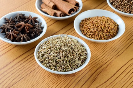 Mixed spice anise, aniseed, cinnamon, fenugreek in bowl over wooden backgroundの写真素材