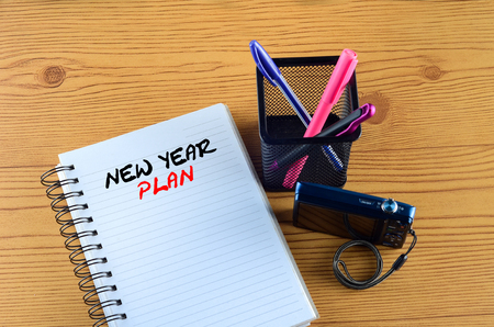 NEW YEAR PLAN written on book. Office desk with  ring book, pen, and camera conceptの写真素材