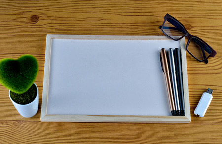 Business concept - Office desk with White board, pendrive, glasses, pen, and table flower. Space for...