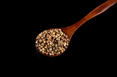 Spice seed in wooden spoon over black backgroundの写真素材