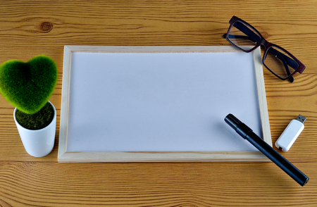 Business concept - Office desk with White board, pendrive, glasses, pen, and table flower. Space for text available.の写真素材