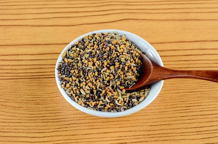 Mixed Fenugreek Spice in white bowl with wooden spoon over wooden backgroundの写真素材