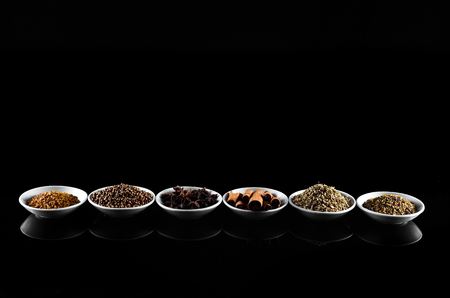 Mix Spice anise aniseed cinnamon fenugreekwith space for text in white bowl over black backgroundの写真素材