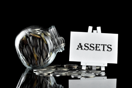 Business Concept - Money in glass containe and white board written Assetsの写真素材
