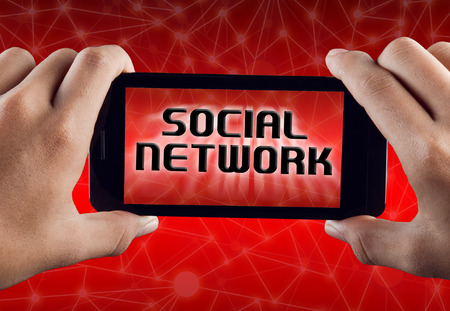 Hand Holding Smart Phone with text Social Network over abstract technology polygonal backgroundの写真素材