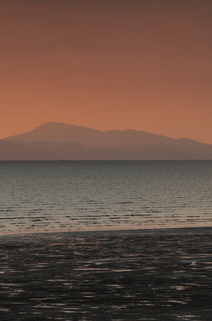 Beautiful sunset view with wooden structure in the sea over majestic scenery of ocean and mountainの写真素材