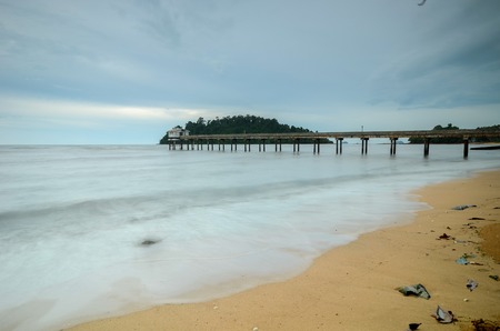 Beautiful Beach with jetty structure to ocean on overcast dayの写真素材