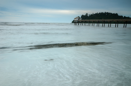Beautiful Beach with jetty structure to ocean on overcast dayの写真素材
