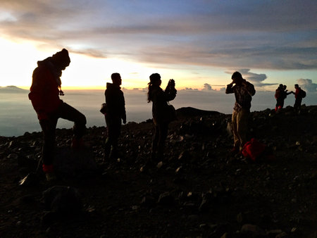 Silhouette of a group of tourists on top of a mountain during sunset