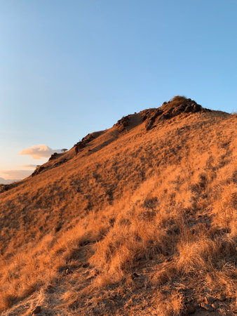 Sunset at the top of the mountain with dry grass and blue skyの写真素材