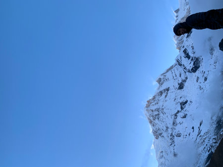 Hiker on the top of a snowy mountain with blue sky backgroundの写真素材