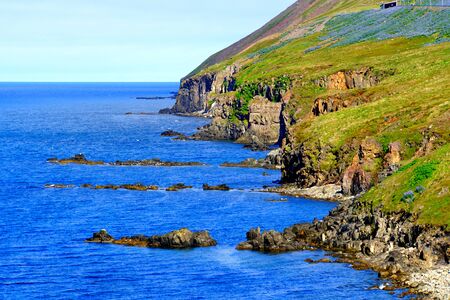 Spectacular view of the cliffs and rock formation by the ocean in the summer near Olafsfjordur, Icelandの写真素材