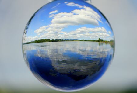 Beautiful lake, white clouds and blue sky captured through a crystal lens ball