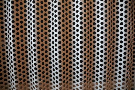 Background of black holes pattern and shades on a metal sheetの写真素材