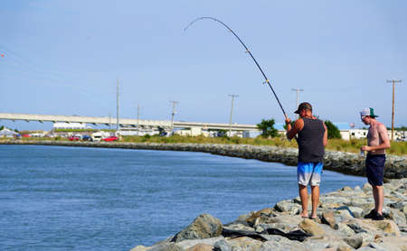 Bethany Beach, Delaware, U.S.A - September 2, 2019 - A man fishing by the rocks by Indian River...