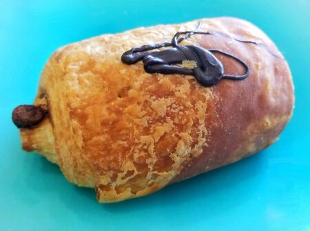 Chocolate croissant on a light blue isolated background