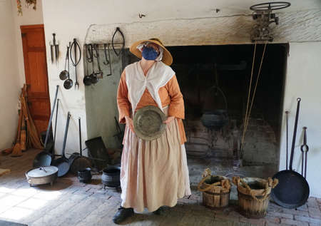 Williamsburg, Virginia, U.S.A - June 30, 2020 - A lady inside a kitchen wearing a mask as required...