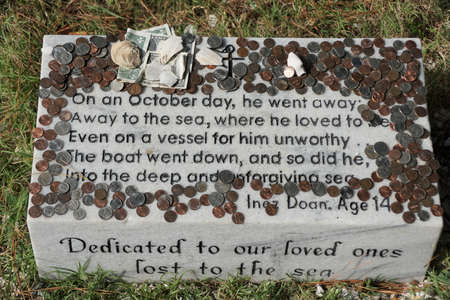 Chincoteague, Virginia U.S.A - September 21, 2021 - A stone with remembrance of the missing fisherman and money left by visitors under the Assateague Light Houseのeditorial素材
