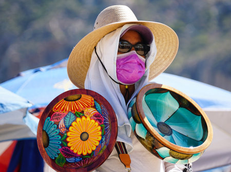 Cabo San Lucas, Mexico - November 7, 2022 - A local salesperson offering colorful bowls for sale on a sunny dayのeditorial素材