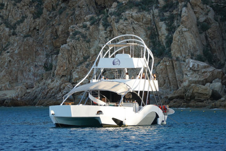 Cabo San Lucas, Mexico - November 7, 2022 - A luxury boat docked by the shallow water near the rock formationのeditorial素材