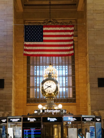 New York City, U.S.A - October 31, 2022 - The large gold clock under American flag inside of the Grand Central Terminalのeditorial素材