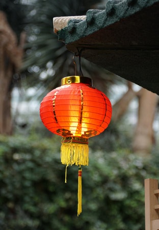 A Chinese red lantern hanging on the side of a roof