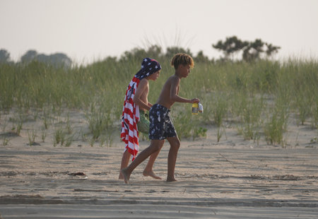 Rehoboth Beach, Delaware, U.S.A - June 18, 2023 - Two kids walking on the sand near the beach dunesのeditorial素材