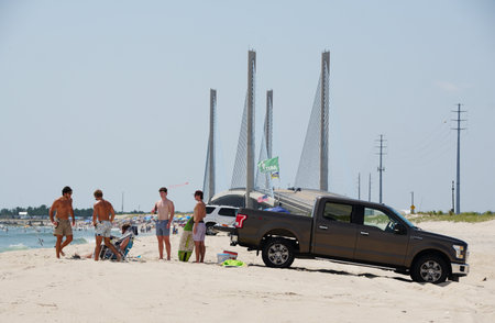 Faithful Steward, Delaware, U.S.A - August 4, 2023 - People and vehicle with surf fishing beach permit with the background of the Indian River Bridgeのeditorial素材
