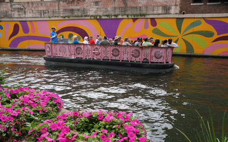 San Antonio, Texas, U.S - April 6, 2024 - The Go Rio River Boat tours carrying visitors passing the colorful mural on the water by Dolorosa Streetのeditorial素材
