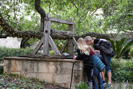 San Antonio, Texas, U.S.A - April 9, 2024 - Visitors checking out the old and historic Alamo well under the oak treeのeditorial素材